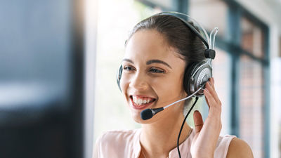 Similing Worker At Computer Wearing Headset 