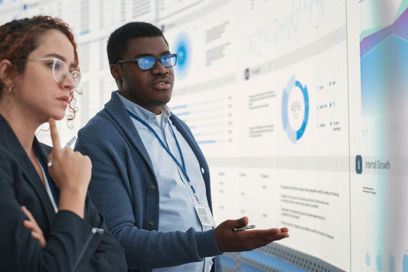 Colleagues Reviewing Data On Large Screens 