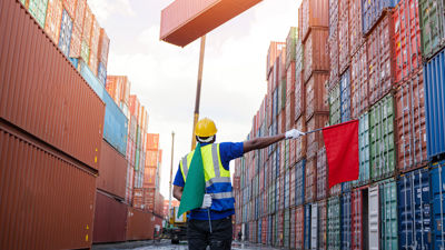 Worker Directing Crane Stacking Cargo Containers 