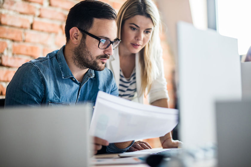 Colleagues Reviewing Documents Near Desktop
