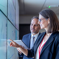Colleagues Discussing Data On Wall Of Screens 