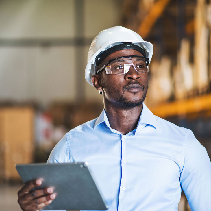 Person Wearing Safety Gear Working In Warehouse With Tablet 