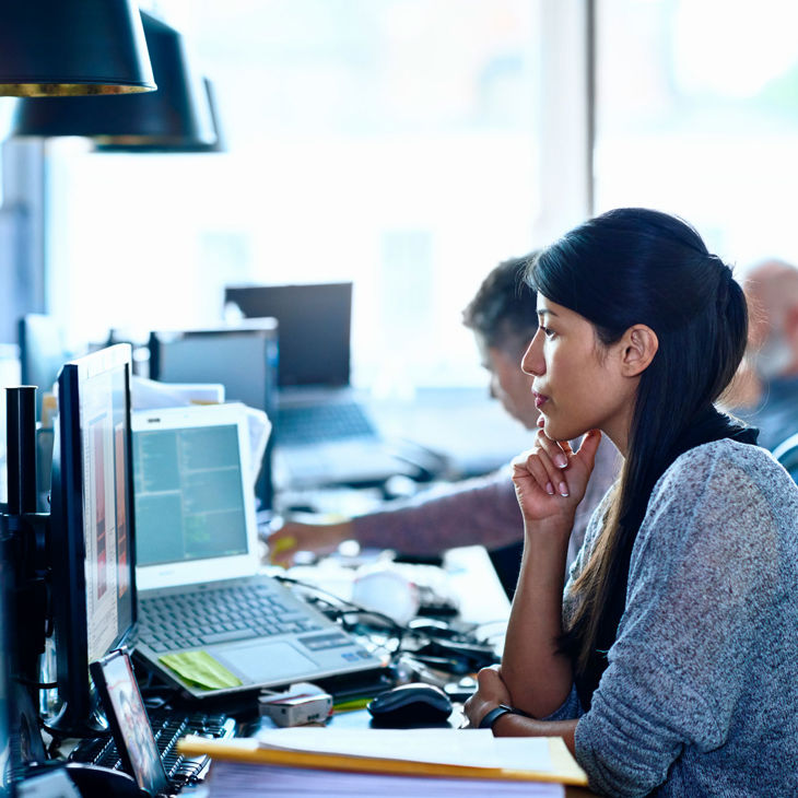 Person Reviewing Data On Office Screens 