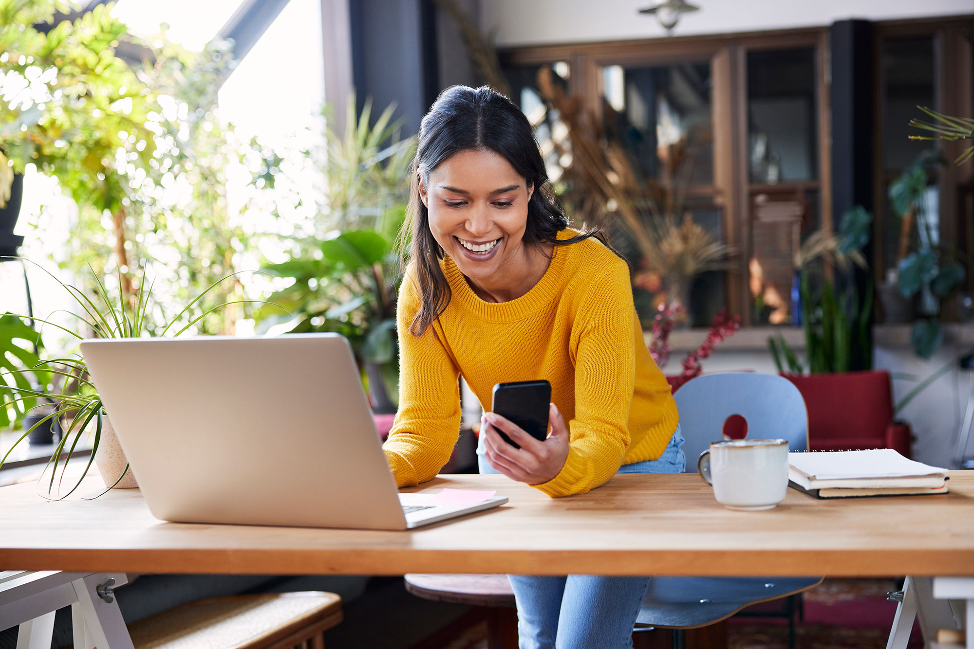 Person Smiling At Phone Over Laptop 
