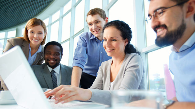 Group Of Happy Coworkers Looking At Laptop 