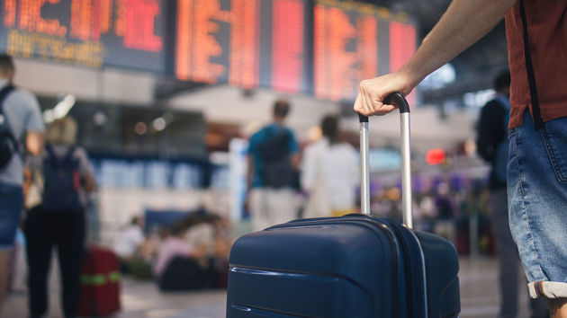Hand Holding Suitcase In Airport Terminal 