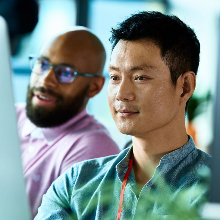 Confident Man At Computer With Colleague 