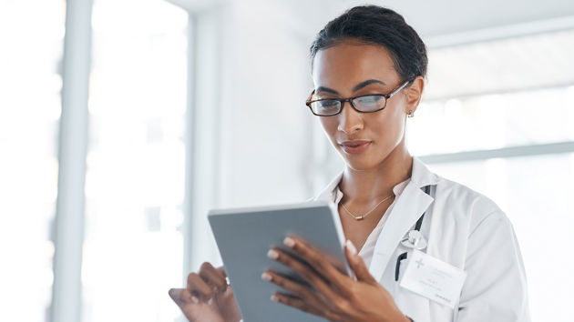 Doctor Reviewing Info On Tablet 