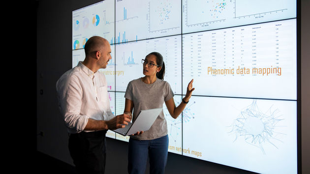 Colleagues Discussing Data Points Shown On Screens 